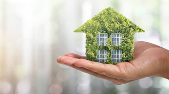 Manos sujetando una casa de verde como modelo sostenible