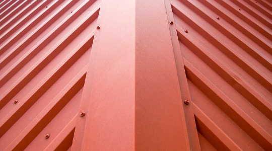 Primer plano de una cumbrera instalada en un techo de lámina metálica rojiza - Cumbreras
