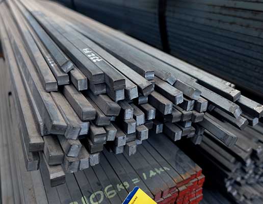 Barras cuadradas macizas de acero apiladas dentro de una bodega