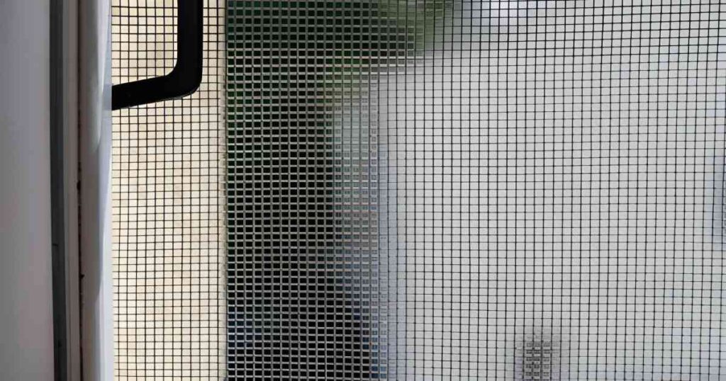 Plano detalle de una malla mosquitera instalada en una ventana