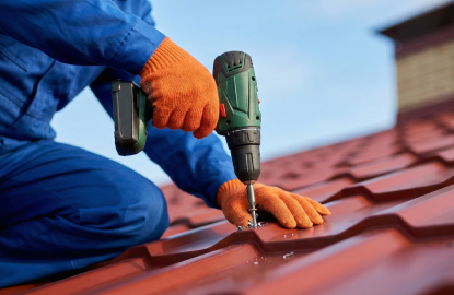 Hombre realizando instalación de lámina tipo teja con un taladro