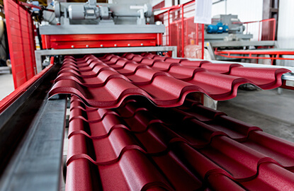 Láminas tipo teja metálicas saliendo de roladora industrial