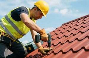 Hombre con taladro atornillando sobre techo tipo teja de metal