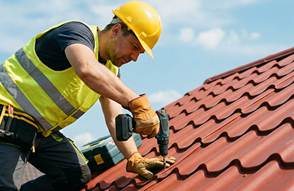 Hombre con taladro atornillando sobre techo tipo teja de metal
