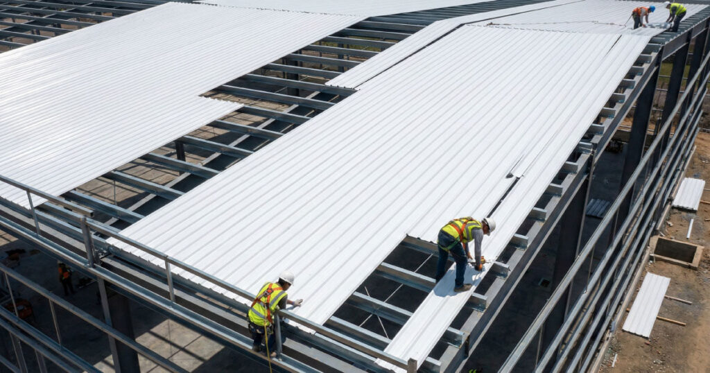 Trabajadores instalando lámina acanalada Pintro en techo de nave industrial en construcción