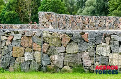 Cerca de mampostería fabricada con piedras y sostenia por gaviones de alambre